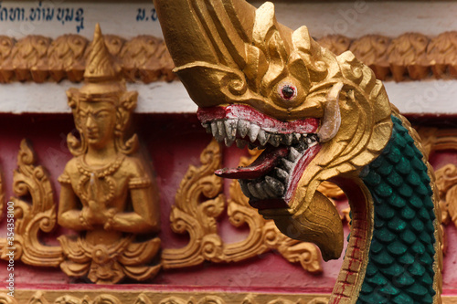 Tip of a stony and golden painted stupa in front of a religious wooden monks building or home in Siamese Lao PDR, Southeast Asia
