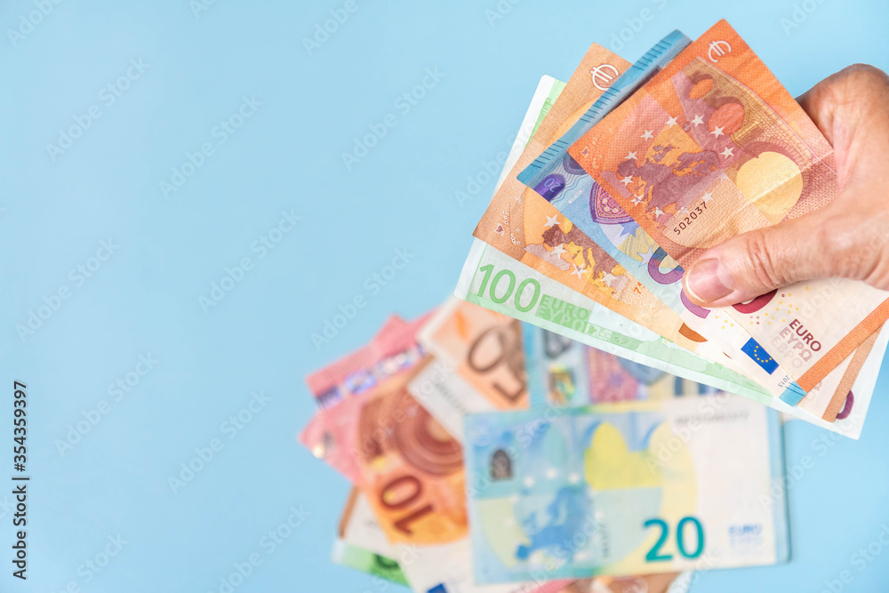 Hand holding euro banknotes isolated on azure background with copy space Hand holding euro banknotes isolated on azure background with copy space