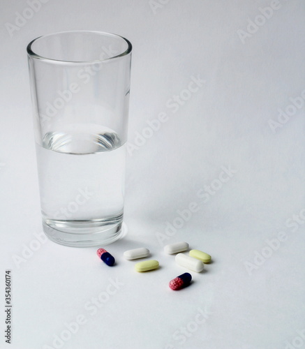  medicines, pills and a glass of water on a white background