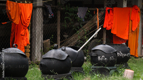 Garbage containers and management in a temple environment showing an orange monks dress in the back in Siamese Lao PDR, Southeast Asia