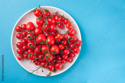 Bunch of bright fresh red cherry tomatoes on round plate