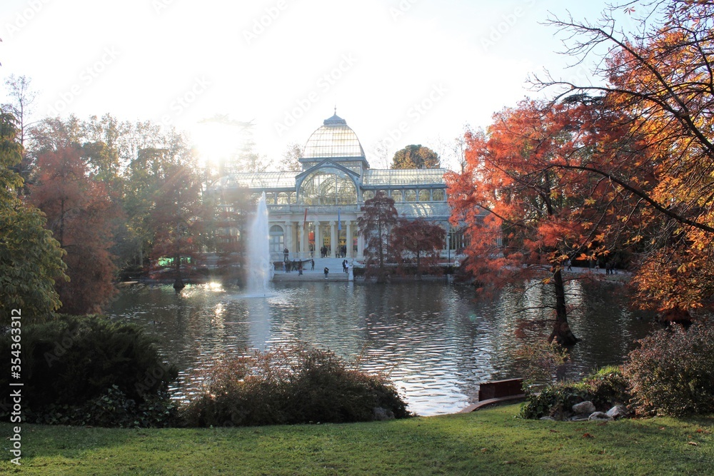 Vista del Palacio de Cristal del parque del Retiro con su estanque en otoño
