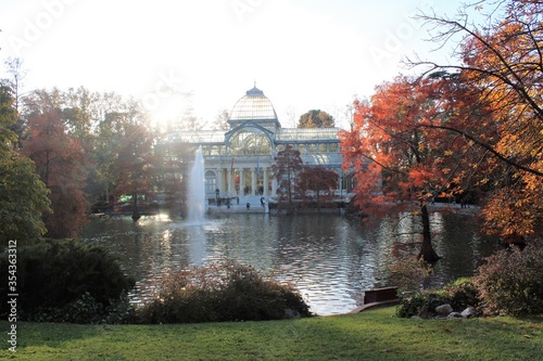 Vista del Palacio de Cristal del parque del Retiro con su estanque en otoño