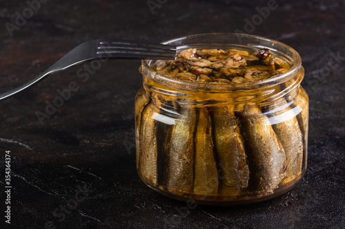 Glass jar of sprots with a fork on a concrete background photo