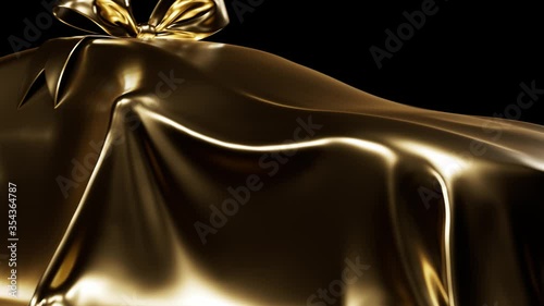 Expensive car gift covered by gold shiny fabric with bow-knot isolated on a black studio background. Luxury surprise item. Golden cloth.