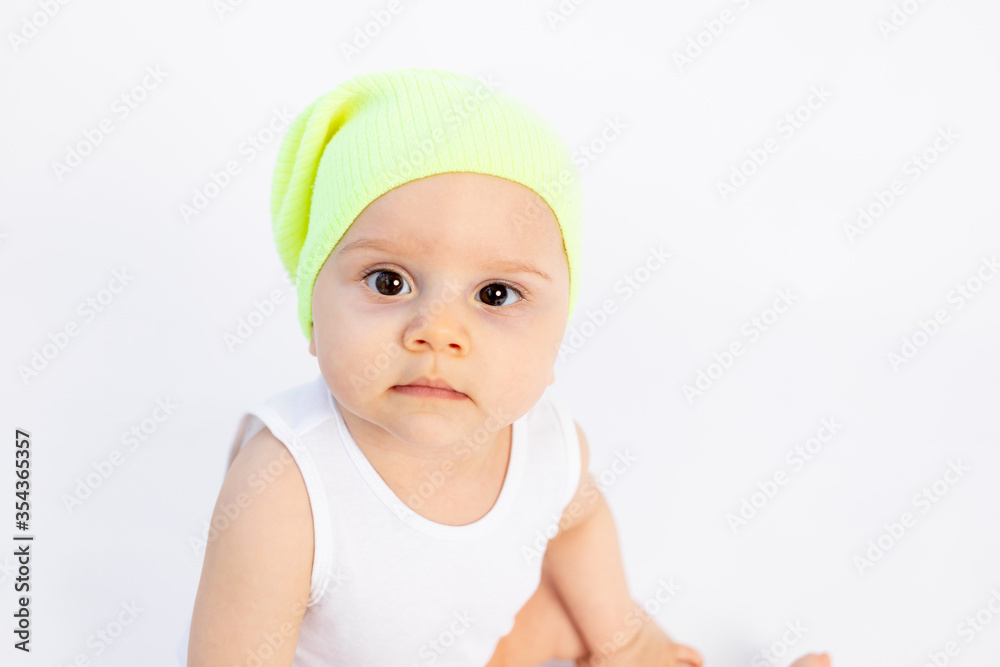 small child boy 8 months old sitting on a white background in a hat, portrait, up to a year, space for text small child boy 8 months old sitting on a white background in a hat, portrait, up to a year, space for text