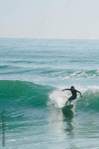 Canvas Print A surfer dressed in wetsuit surfing on a blue wave at sunrise in Valencia in the