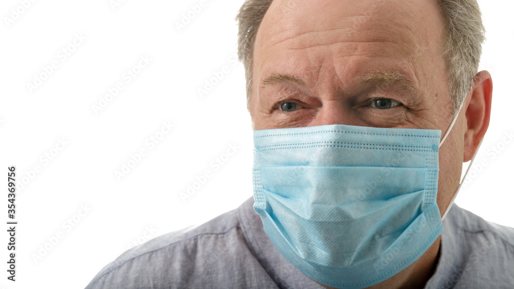 Elderly smiling man in a blue medical mask during corona quarantine Elderly smiling man in a blue medical mask during corona quarantine