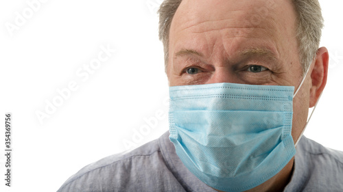Elderly smiling man in a blue medical mask during corona quarantine
