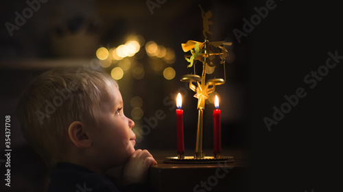 Foto Little boy is looking at candels and angel chimes and hearing ringing, banner co
