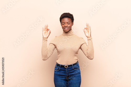 young pretty black womanlooking concentrated and meditating, feeling satisfied and relaxed, thinking or making a choice photo