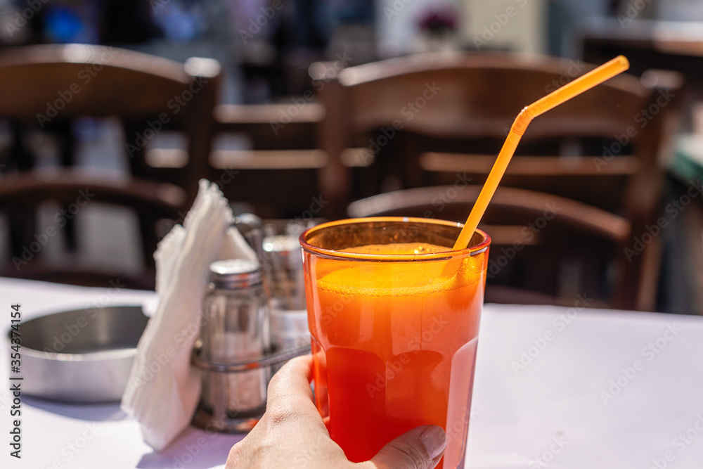 Orange juice in a glass in female hands with a straw Orange juice in a glass in female hands with a straw