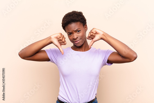 young pretty black womanlooking sad, disappointed or angry, showing thumbs down in disagreement, feeling frustrated photo