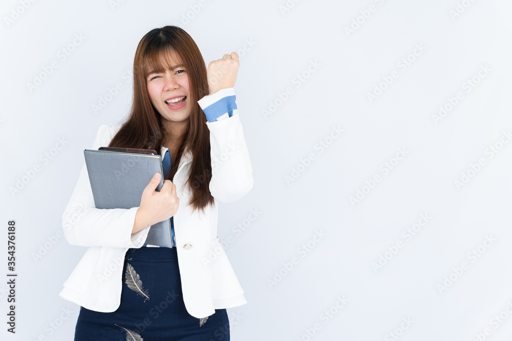 Smiling Asian business woman wearing a medical face mask holding the notebook and showing fist fighting over grey background. Back to the normal concept. Smiling Asian business woman wearing a medical face mask holding the notebook and showing fist fighting over grey background. Back to the normal concept.