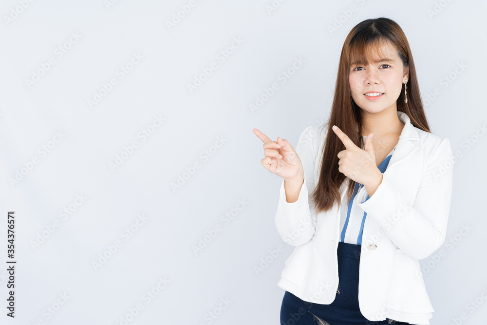 Smiling Asian business woman wearing a medical face mask and pointing hand to side blank space over grey background. Back to the normal concept. Smiling Asian business woman wearing a medical face mask and pointing hand to side blank space over grey background. Back to the normal concept.