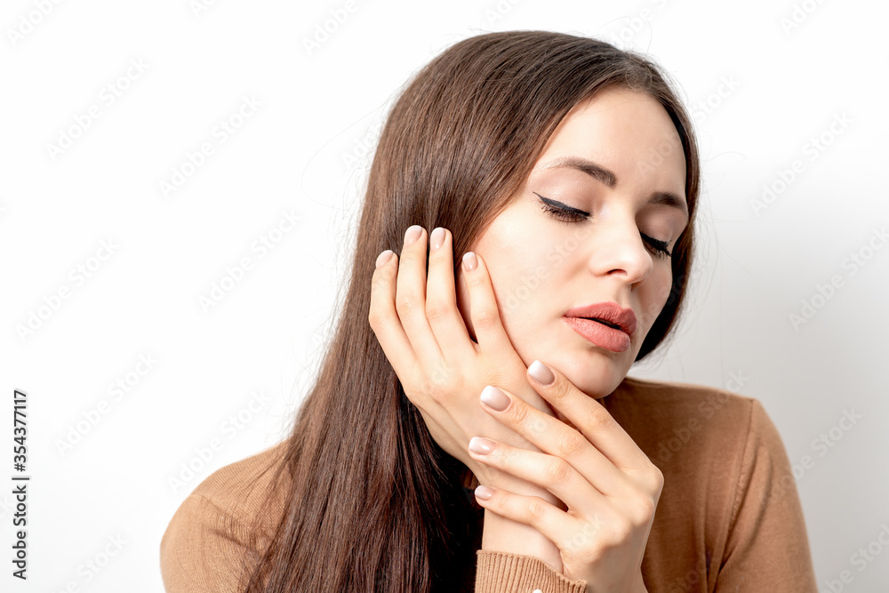 Portrait of pretty young woman touching face with her hand beige manicure on white background with copy space. Portrait of pretty young woman touching face with her hand beige manicure on white background with copy space.