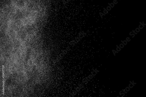 Abstract splashes of water on black background. Freeze motion of white particles. Rain, snow overlay texture.