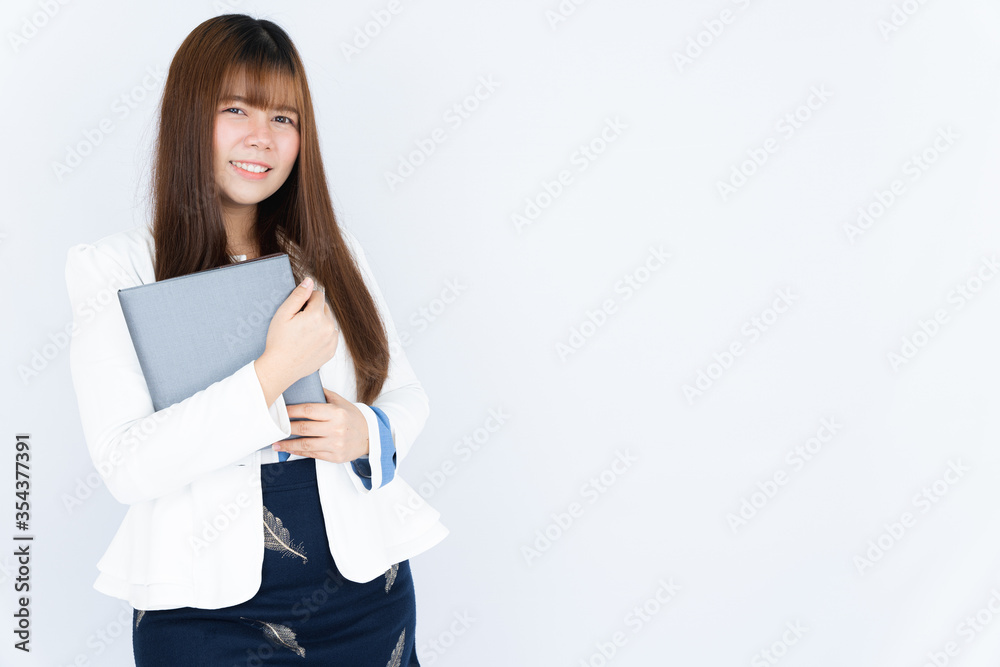 Smiling Asian business woman holding the notebook and looking at the camera over grey background. Back to the normal concept. Smiling Asian business woman holding the notebook and looking at the camera over grey background. Back to the normal concept.