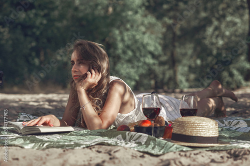 The portrait of young beautiful girl lying on a blanket in a park on the nature