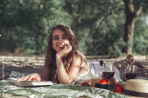 The portrait of young beautiful girl lying on a blanket in a park on the nature