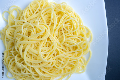 Close up of spaghetti noodles are cooked and then put on a white plate to create curl circles.