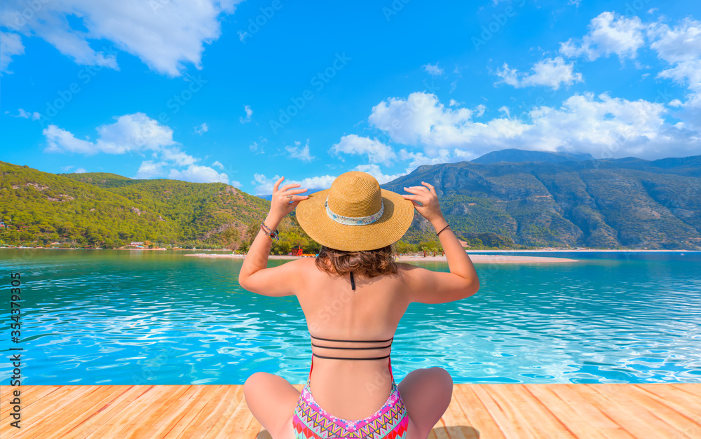 Young girl in hat sunbathes on a wooden pier and summer landscape on the sea - Oludeniz Beach And Blue Lagoon, Oludeniz beach is best beaches in Turkey - Fethiye, Turkey