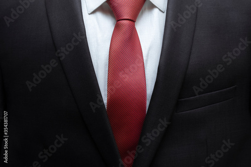 Closeup of black business suit with white shirt and red tie. Businessman in a black suit with a red tie. Business concept.