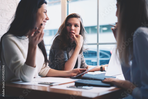 Modern three female colleagues brainstorming about work