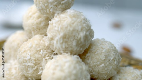 Sprinkling desiccated coconut on top of a pyramid shape coconut chocolates bowls in a half coconut on the table. Concept of preparing white coconut chocolate.