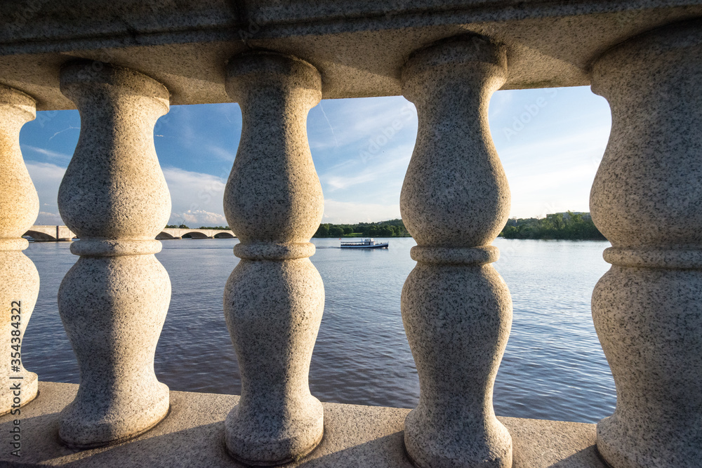 Fototapeta premium Potomac River as seen through bridge columns with boat and Arlington Memorial Bridges.