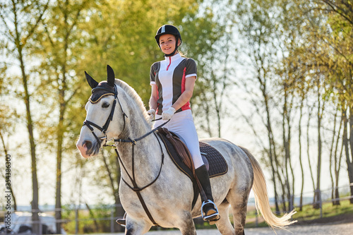 Girl equestrian rider riding a beautiful white horse
