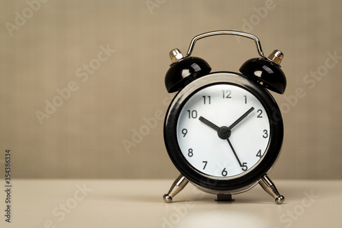 Black retro alarm clock with bells on a wooden table, daily routine concept.