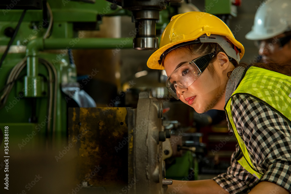 Female worker wearing hard hat are working in industrial plants that have machines. Female worker wearing hard hat are working in industrial plants that have machines.