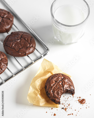 bited dark chocolate cookies on baking tray serving with a glass of milk. concept of delicious homemade dessert or snack good for kids and party.