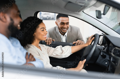 Couple Choosing New Vehicle Talking With Dealer Sitting In Auto