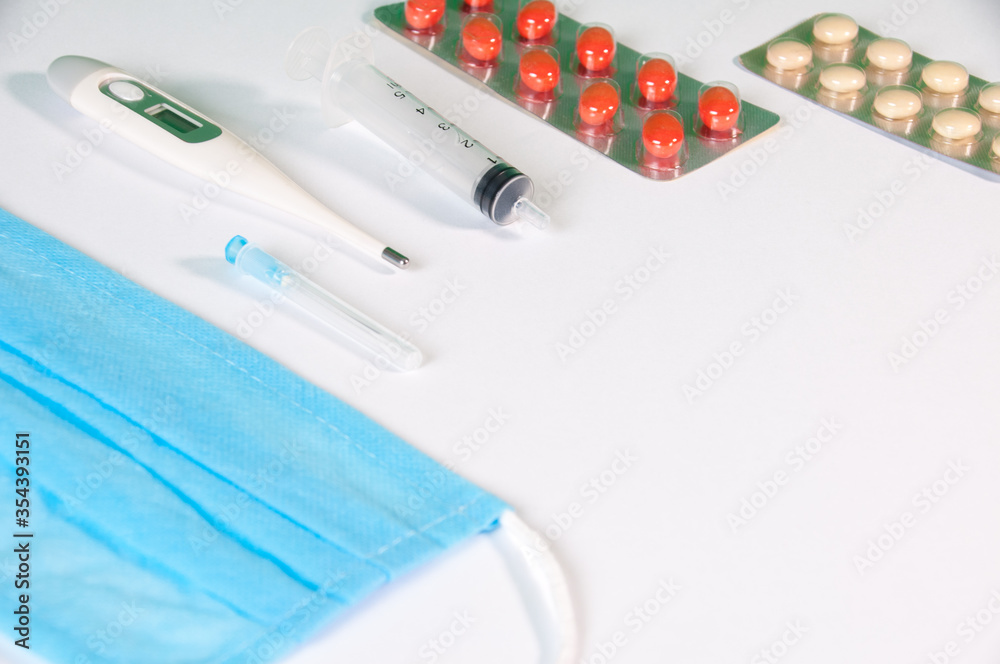 Tablets And A Protective Blue Mask Lie On A White Background Tablets And A Protective Blue Mask Lie On A White Background