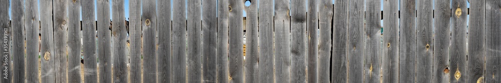 Old wooden fence with slits and holes. Panorama of the fence for use on the site. Background and texture Old wooden fence with slits and holes. Panorama of the fence for use on the site. Background and texture