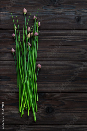 Green onions on a dark wooden background with copyspace for text. Fresh garden herbs  spring onion with flowers.