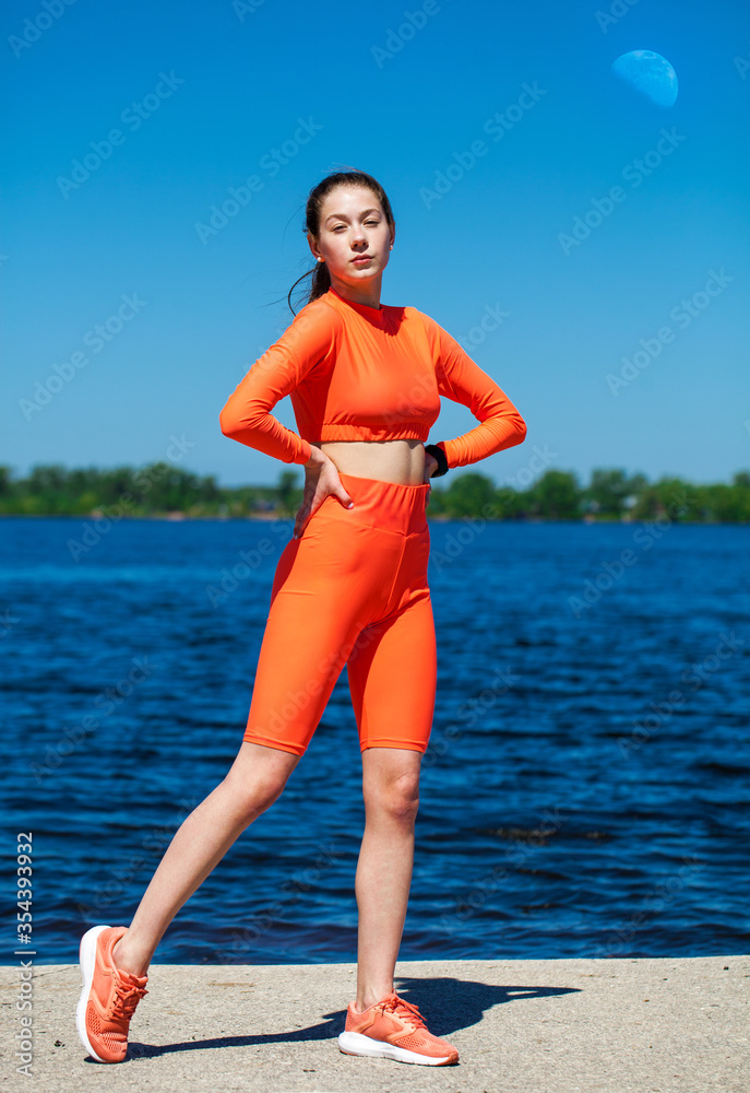 Fototapeta premium Young athletic girl does physical exercises on the banks of the Volga River