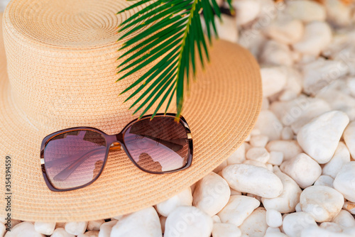 Summer hat, sunglasses under palm tree. Beach accesories , Summer conceprt background. vacation wallpaper. Tropical paradise.