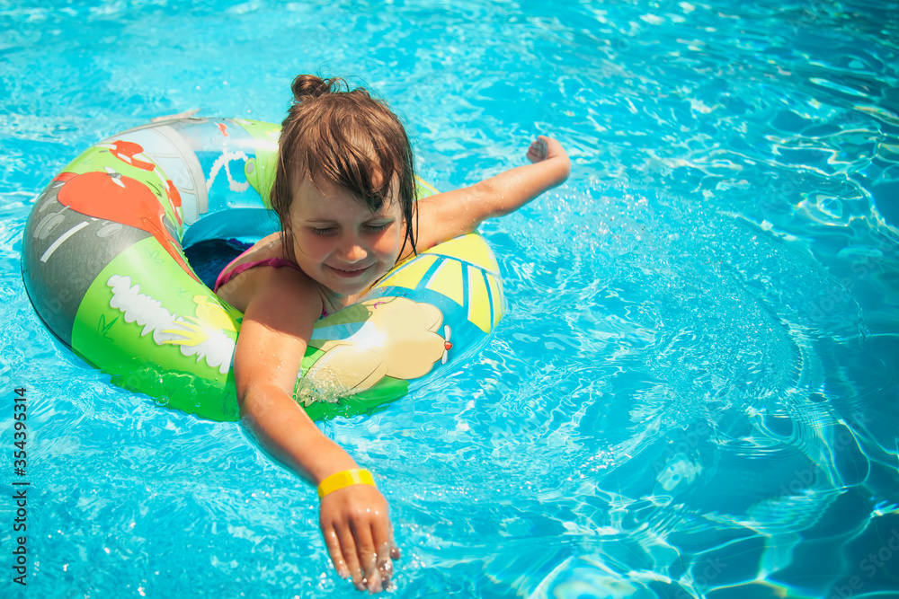 Summertime fun. Pretty little girl swimming in outdoor pool.