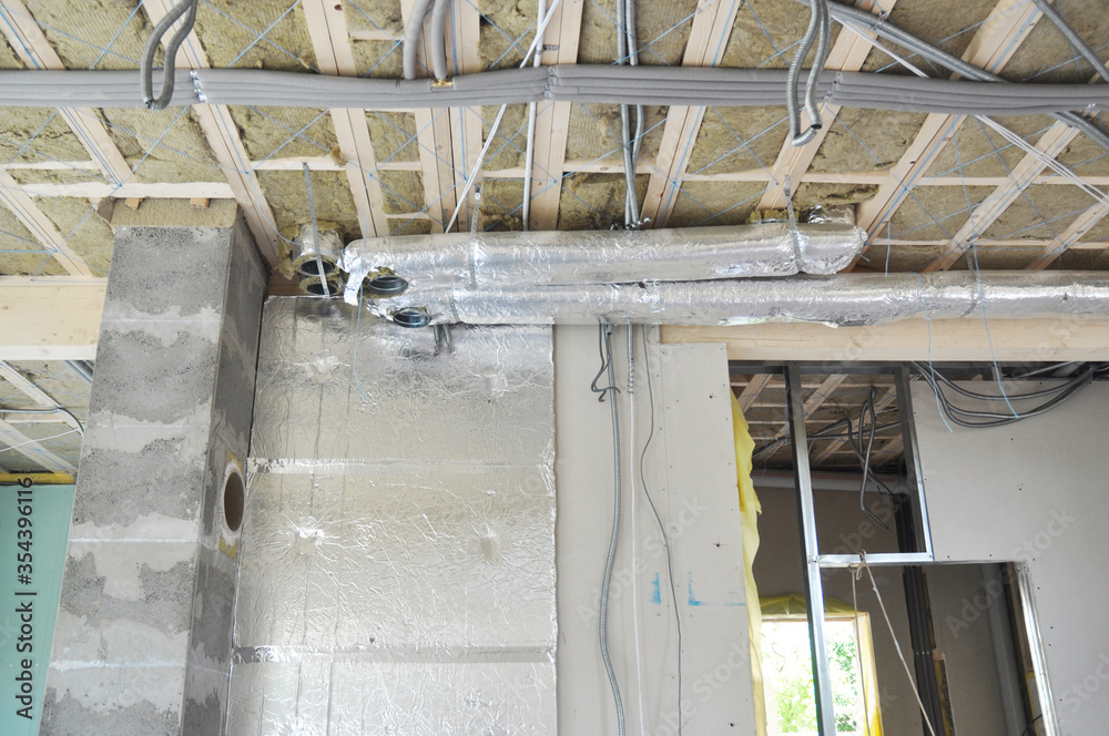 Fototapeta premium Renovating house indoors with air ventilation system, glass wool insulated ceiling, isolated electric wires, water pipes of radiant floor heating system, chimney breast plastering and wall layers.