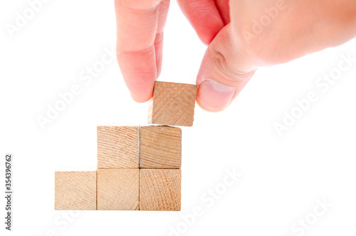 Wooden cubes on a white background. Cubes in the form of stairs, career climb. The male hand puts, lays the top cube on top