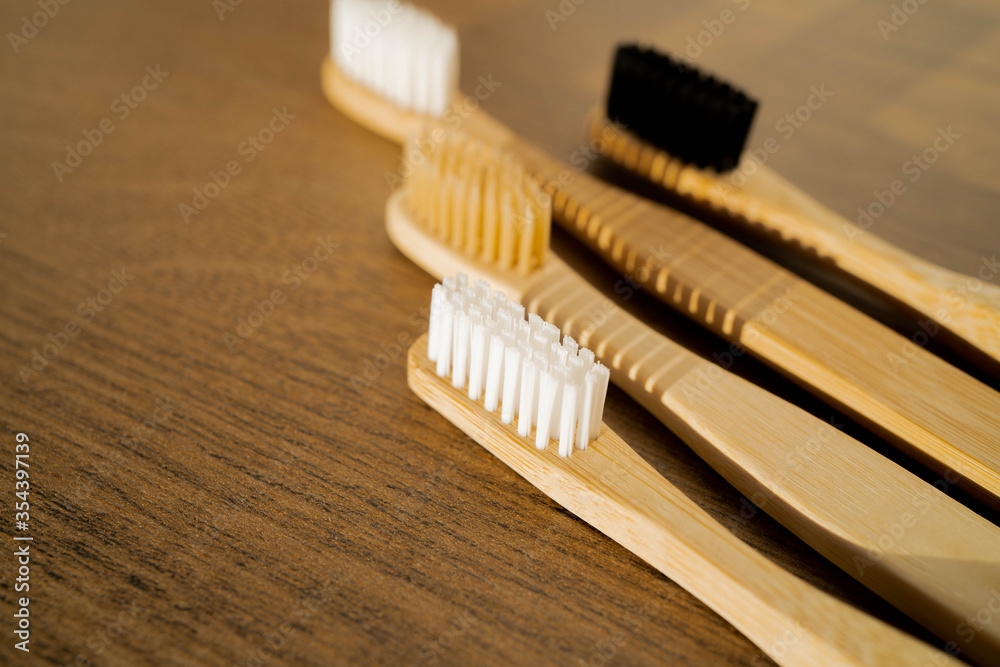 Eco-friendly bamboo toothbrushes on wooden background. Natural organic bathroom beauty product concept. Flat lay, top view, copy space.