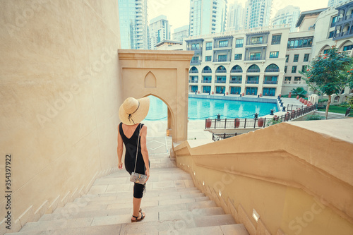Photography Beautiful young woman in black dress with hat walking on Dubai Downtown