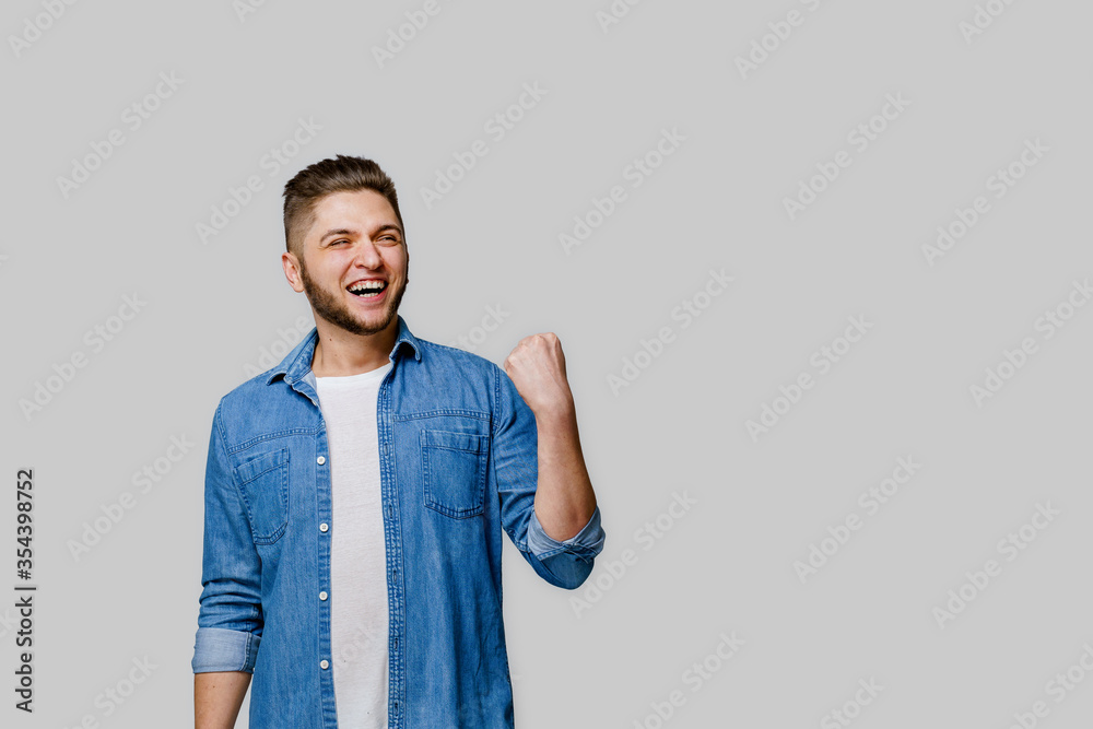 Happy handsome man wins online bet and making crazy emotions. Caucasian man wears denim shirt and smiles . Isolated white backround. Online work at home quarantine concept Happy handsome man wins online bet and making crazy emotions. Caucasian man wears denim shirt and smiles . Isolated white backround. Online work at home quarantine concept