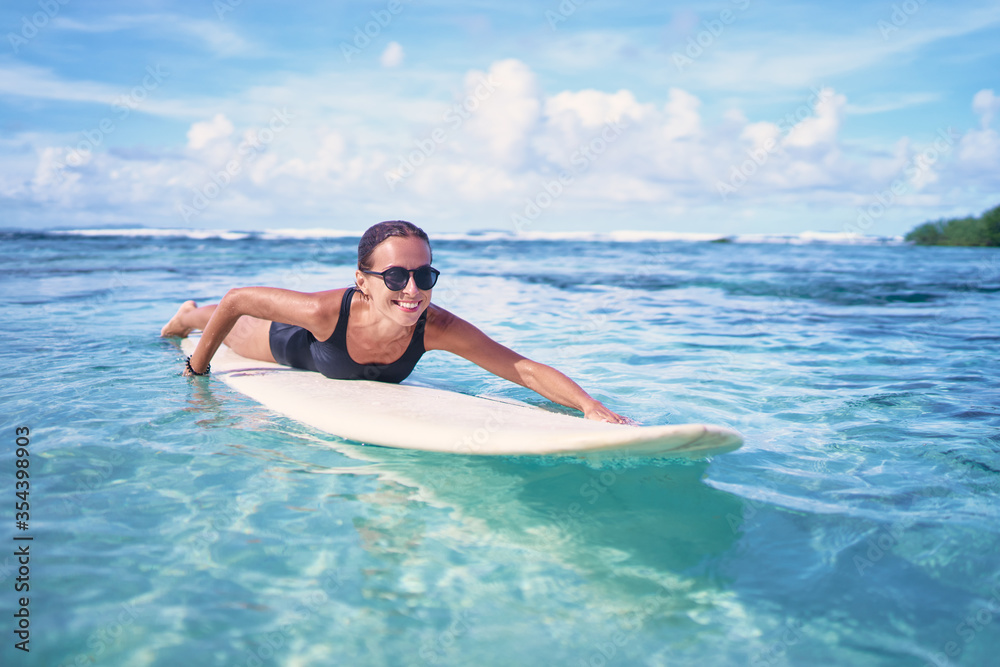 Portrait of surfer woman surfing having fun on Siargao Beach, Philippines. Female girl laughing on surfboard smiling happy living healthy lifestyle.