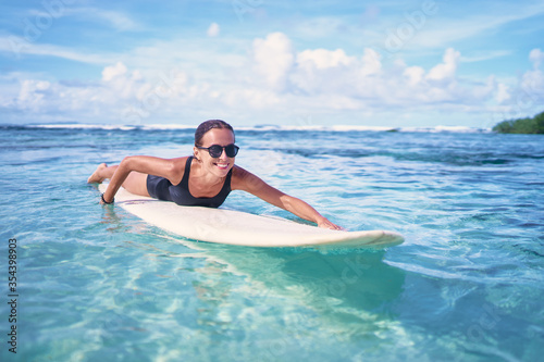 Portrait of surfer woman surfing having fun on Siargao Beach, Philippines. Female girl laughing on surfboard smiling happy living healthy lifestyle. © luengo_ua