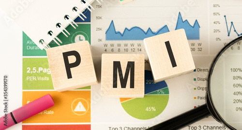 Text PMI on wood cube and gold pen lay on chart candle document paper , economic data concept. photo