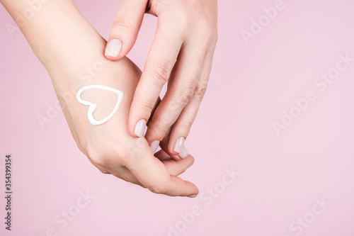 Well-groomed women's hands and cream in the form of a heart on the skin. Gentle manicures and taking care of yourself.